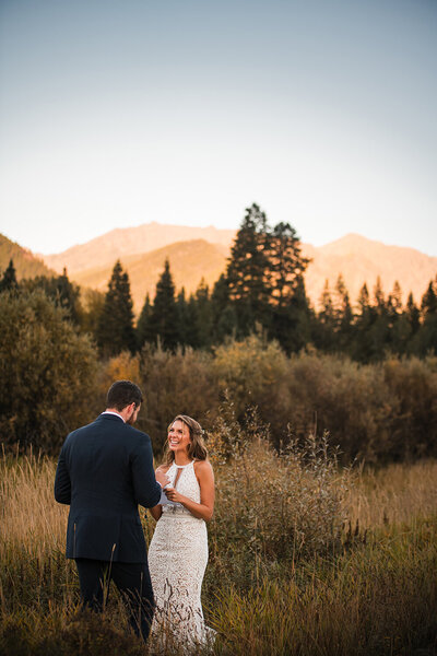 A bride and groom laugh together beneath the rocky mountains of western Montana.