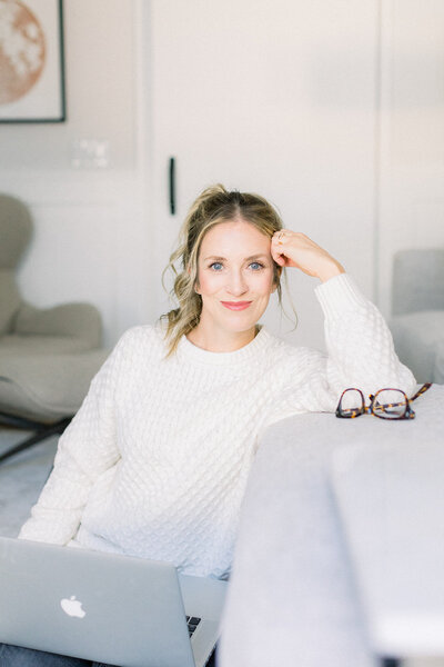 Blonde woman sitting casually with her laptop on a couch