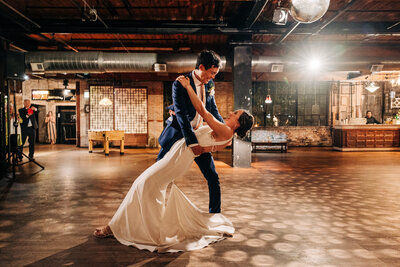Sophisticated bride and groom share an intimate moment dancing together alone in their wedding venue.