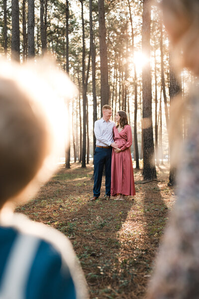 A glowing mother cradles her baby bump in a serene outdoor setting, celebrating a maternity milestone in Tomball, Texas