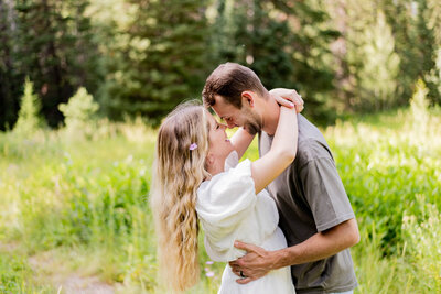 A man is slightly dipping a woman, touching noses with her, and smiling