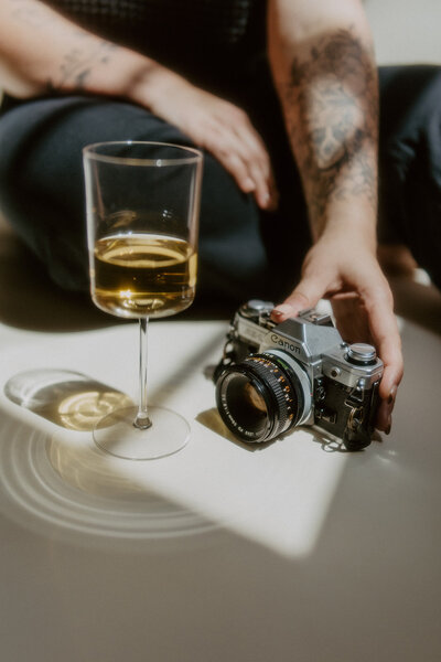Wedding Photographer Jessica Cameron holds her camera next to a glass of champagne