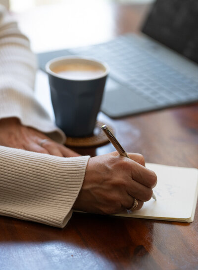 We see the hands of a women taking notes in a small notebook