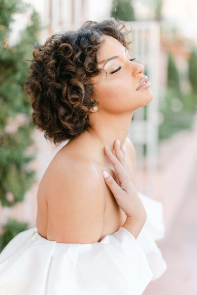 Bride sitting at table with windows behind, leg kicked out wearing tall heels