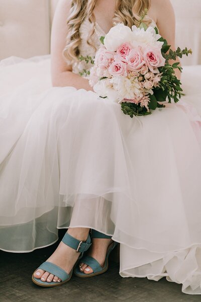 Detail photo of bride and bridesmaid holding Anemone bouquets with heavy greenery and white roses