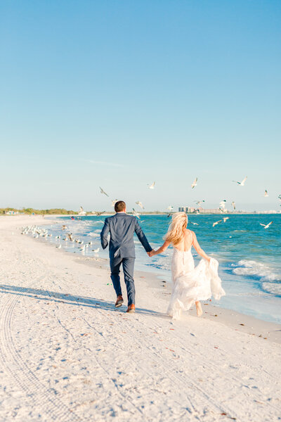 bride and groom running on the beach by wedding photographer naples fl