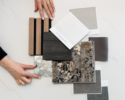 Flatlay of curated material samples selected by Boston interior designer, including fabric swatches, wood tones, and stone tile