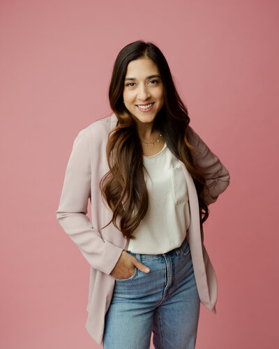 Woman poses for headshot with teal background