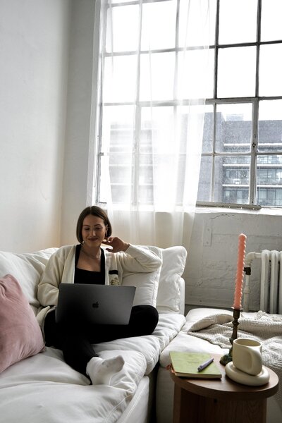 Margarita, website copywriter for creatives, sitting on a white couch  and  smiling at a client who;s on her computer screen