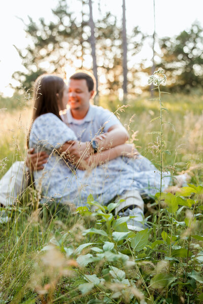 Couple sitting with the background of the setting sun, celebrating their recent engagement.