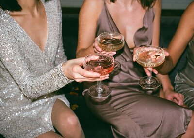 Two women dressed for a night out, clinking glasses in celebration—capturing the polished, refined experience Maven + Grace delivers

