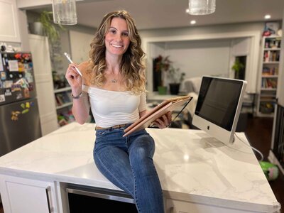 Woman  smiling while sitting  on counter holding an iPad