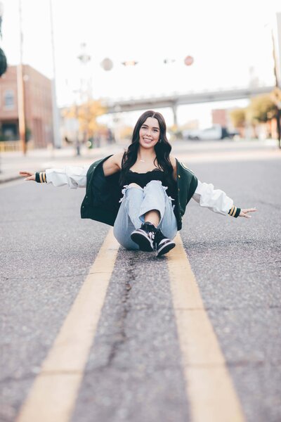 A woman in a white leotard posing in front of a building, captured by Senior portrait photographer Britt Elizabeth.