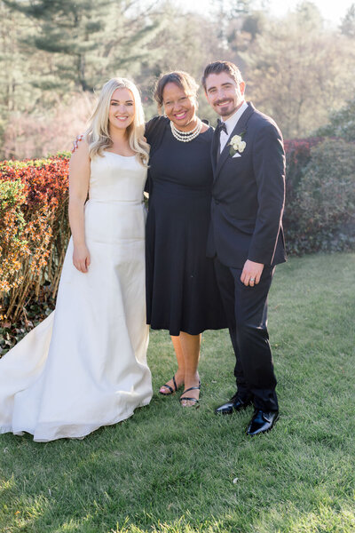 Bride and groom posing outdoors with a wedding planner