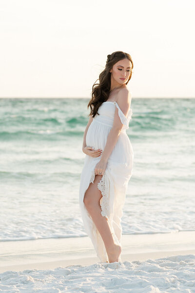 Elegant maternity portrait at the shoreline in golden light, captured by Andrea Krey Photography in Destin, FL