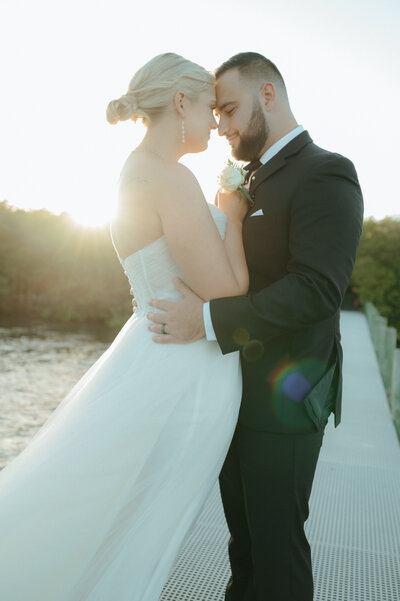 intimate wedding moment between bride adnd groom nuzzled together at golden hour
