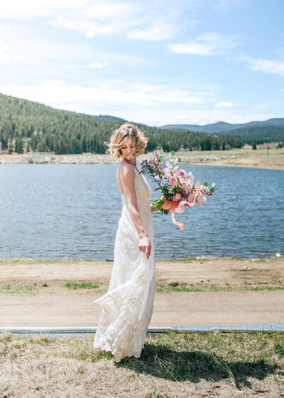 Bride standing in front of lake with flower bouquet for Colorado Springs Wedding