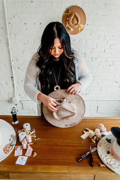 a hat designer making a hat during a branding photo sessionj