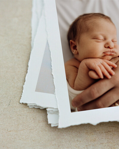 A stack of fine art torn edge prints showing a newborn baby, photographed by newborn photographer lucy jane in christchurch