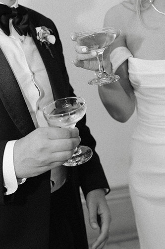 Chic couple de mariés tenant chacun une coupe de champagne. 