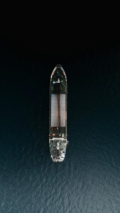 An aerial view of a large cargo ship isolated in open water, highlighting its deck and surrounding deep blue ocean.