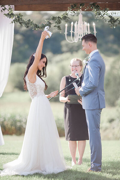Bride raises hand in air during wedding ceremony