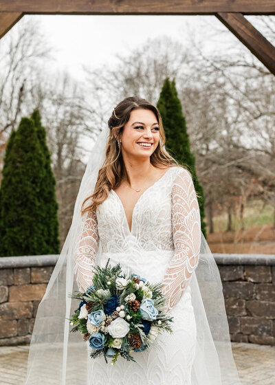 Bride outside in an elegant long sleeved wedding dress, smiling