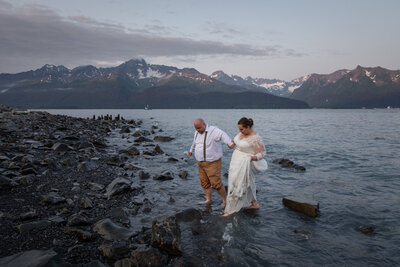 Bride and Groom walk barefoot out of the freezing ocean water of Resurrection Bay in Seward, Alaska.