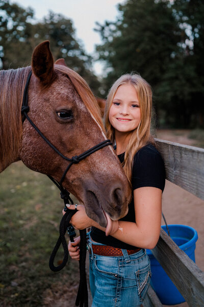 Teen girl poses for the camera with her horse.