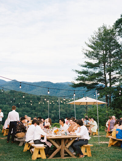 A wider view of the outdoor reception under string lights at wedding venue Paint Rock Farm in scenic North Carolina, by film photographer My Sun and Stars Co.