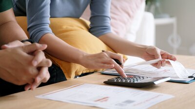 Close-up of couple reviewing receipts and using a calculator at home