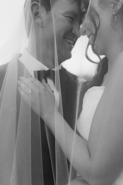 An image of a bride from the neck down holding her heels all in black and white