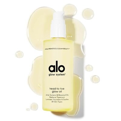 Alo Glow System Head-to-Toe Glow Oil bottle with golden drops of oil on a white background, clean beauty body oil