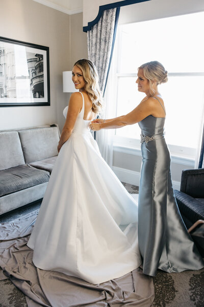 bride getting ready at the fairmont in san francisco, ca, mom zipping up wedding dress
