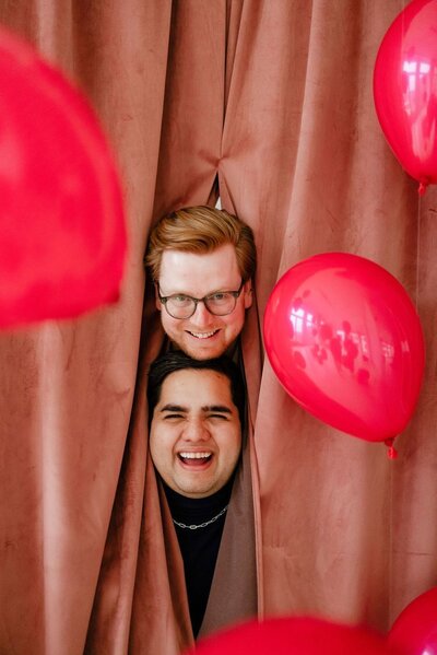 Valentine's Day event at The Studio Chicago with 2 men popping their heads out from behind a pink curtain.