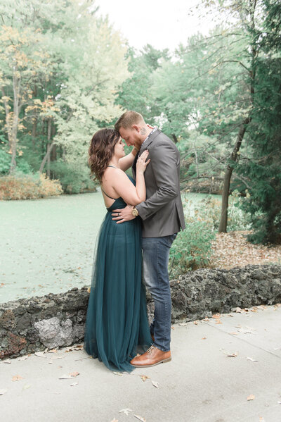 couple holding each other standing on cobblestone bridge at Dow Gardens