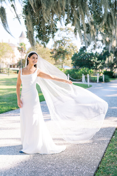 Bride throws veil into the wind on the path of Jekyll Island Club Resort during wedding weekend