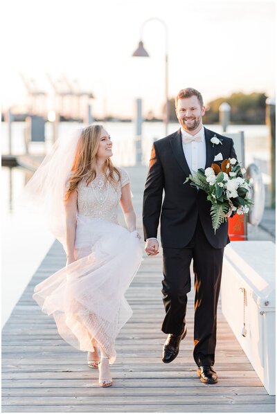 Bride and groom, walk on a dock in Norfolk.