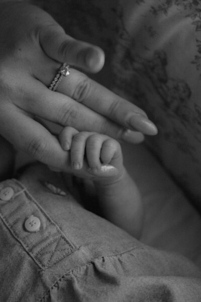 black and white close up of baby holding mom's finger