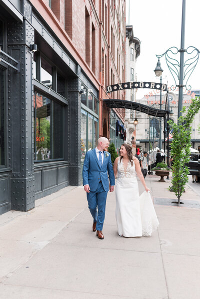 denver wedding photographer captures bride and groom holding hands and smiling at each other for their downtown wedding in denver