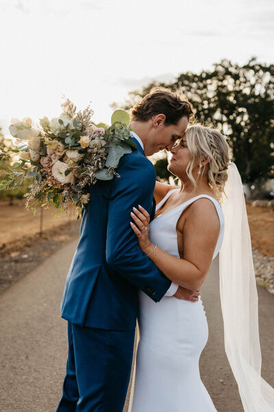 newlyweds embrace on paved path