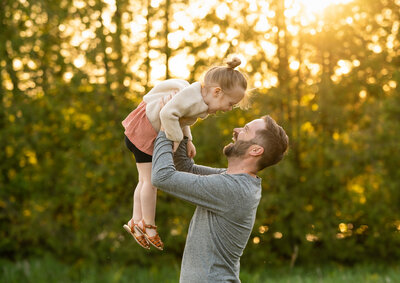 A father holding up his toddler in the air