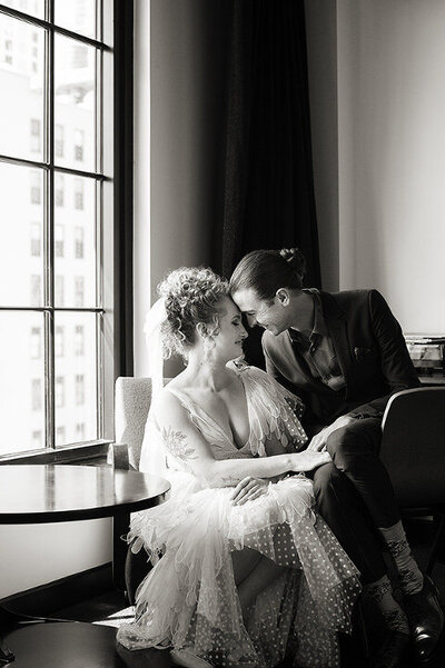 A wedding couple sitting together with their foreheads touching 