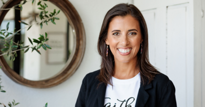 Women in white tshirt with black blazer smiling at the camera.