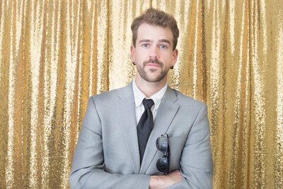 Co Owner of walker booth posing with a suit in front of a sparkly backdrop