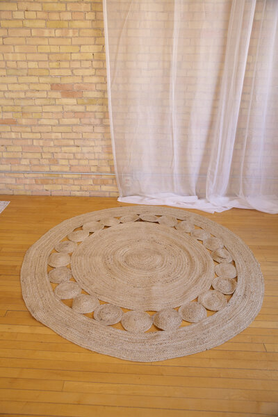A large round jute rug on hardwood floor.