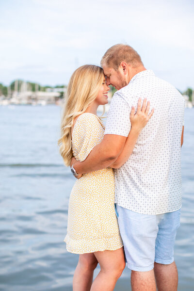 Couple embraces during engagement session in front of water