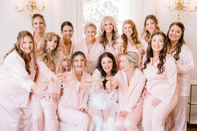 large bridal party toastin in pink pajamas at woodbine mansion wedding venue near austin by texas wedding photographer