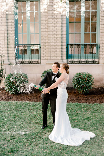 Couple popping champagne for wedding portraits