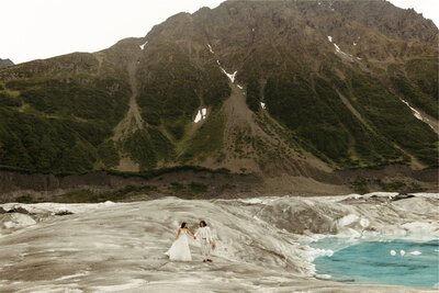 couple walking on a glacier next to the mountains